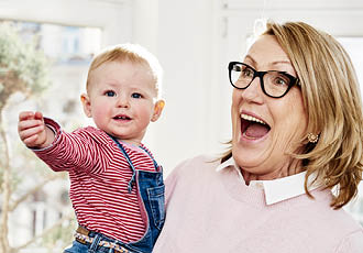 Femme senior avec des verres progressifs portant son petit-fils dans les bras